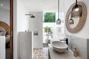 A modern bathroom with a large, round sink, a mirror with a woven frame, and a shower with a black headboard. - Villa Surya Tanah by Alfred in Bali (Seminyak)