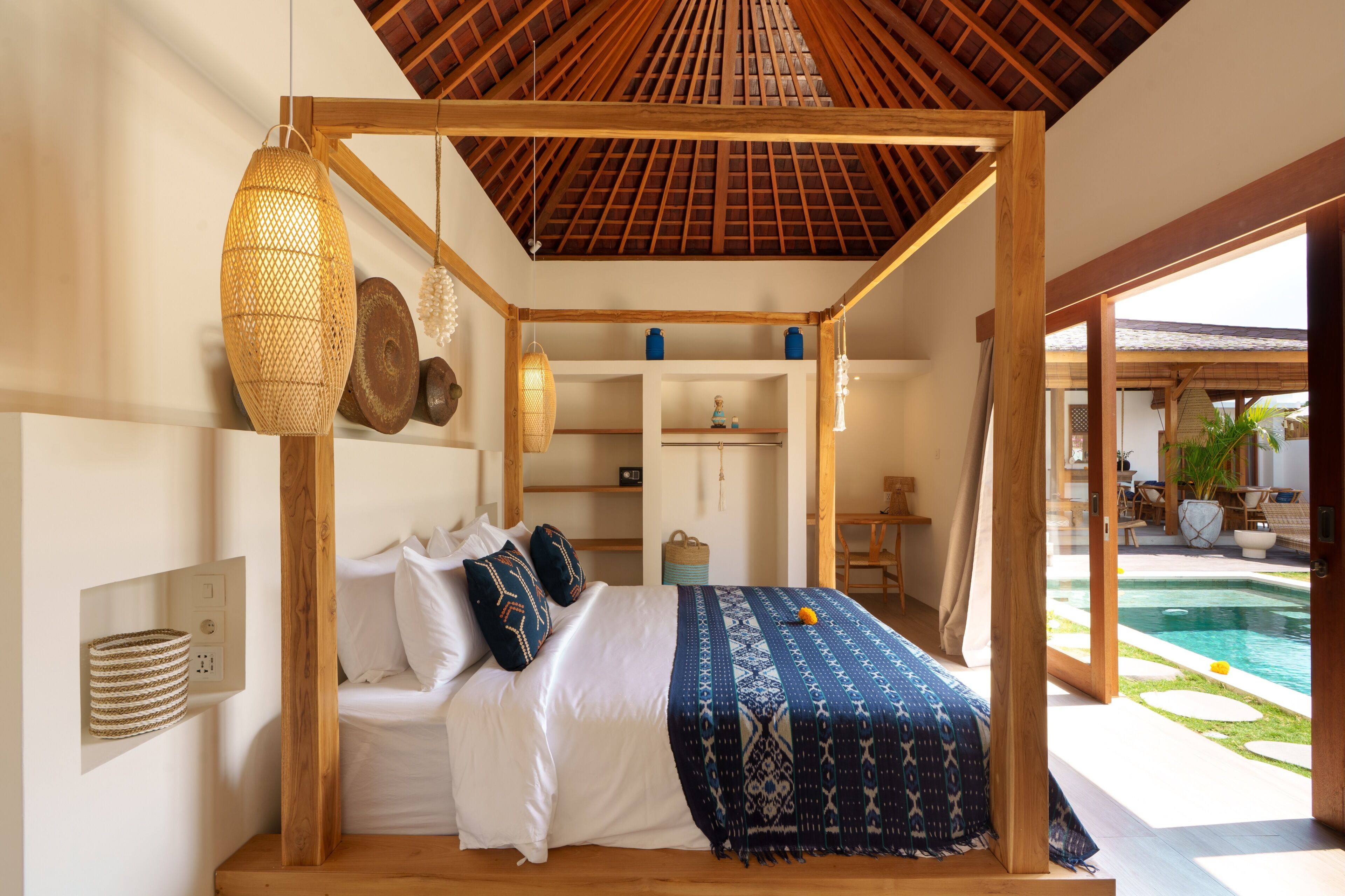Ein Schlafzimmer mit einem Himmelsbett, Nachttischlampen und Blick auf einen Pool.