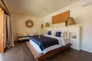 A bedroom with a large bed, a bedside table, a mirror, and a hanging light fixture. - Villa Surya Tanah by Alfred in Bali (Seminyak)