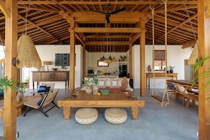 A spacious living area with a wooden ceiling, a central table, and hanging light fixtures. - Villa Surya Tanah by Alfred in Bali (Seminyak)
