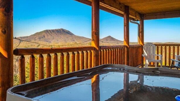 Un bain à remous installé sur une terrasse en bois, avec vue sur les montagnes.