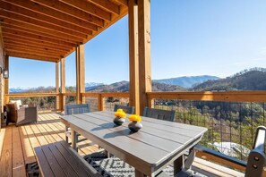 Eine Holterrasse mit Tisch und Stühlen mit Blick auf eine gebirgige Landschaft.
