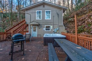 A wooden deck with a hot tub, barbecue grill, and picnic table. - Golden Pines Retreat (Gatlinburg)