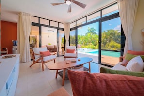 A modern living room with a pool view, featuring a sofa, chairs, and a coffee table. - Villa Tranquila, Luxury Boho Encuentro Retreat (sosua)
