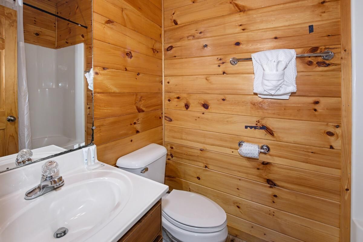 A wooden-paneled bathroom with a sink, toilet, and towel rack.