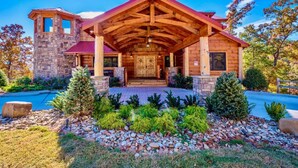 A log cabin with a stone tower, a covered porch, and a swimming pool. - Summit Castle (Sevierville)