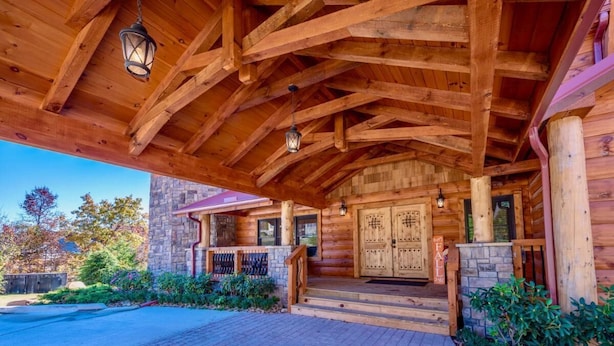 A log cabin with a stone exterior, a wooden porch, and a double door entrance. - Summit Castle (Sevierville)