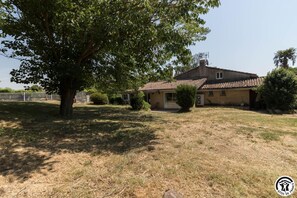 Ein zweistöckiges Haus mit Ziegeldach, umgeben von einem Rasen und einem großen Baum.