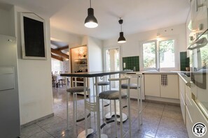 A modern kitchen with a dining area, bar stools, and a view of the outdoors. - La Grangère Vineyard - MONTAUT (MONTAUT)