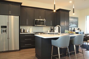 A modern kitchen with dark cabinetry, stainless steel appliances, and a central island with bar stools. - Villa Imperial Bonita Springs 5 minutes to the beach, 4 bed/3 bath (Bonita Springs)