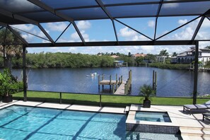 A pool area with a view of a lake, dock, and houses in the background. - Villa Imperial Bonita Springs 5 minutes to the beach, 4 bed/3 bath (Bonita Springs)