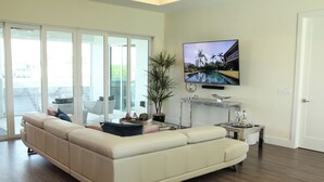 A modern living room with a large sectional sofa, a coffee table, and a flat-screen TV mounted on the wall. - Villa Imperial Bonita Springs 5 minutes to the beach, 4 bed/3 bath (Bonita Springs)