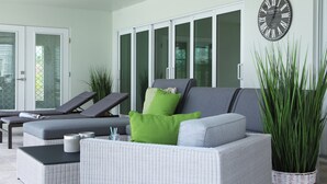 A modern lounge area with a grey sofa, green cushions, and a large potted plant. - Villa Imperial Bonita Springs 5 minutes to the beach, 4 bed/3 bath (Bonita Springs)