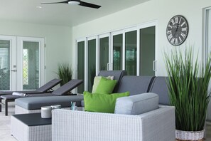 A modern lounge area with a grey sofa, green cushions, and a large potted plant. - Villa Imperial Bonita Springs 5 minutes to the beach, 4 bed/3 bath (Bonita Springs)