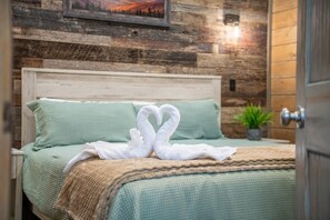 Uma cama com um cobre-leito verde e uma toalha disposta em forma de cisne.