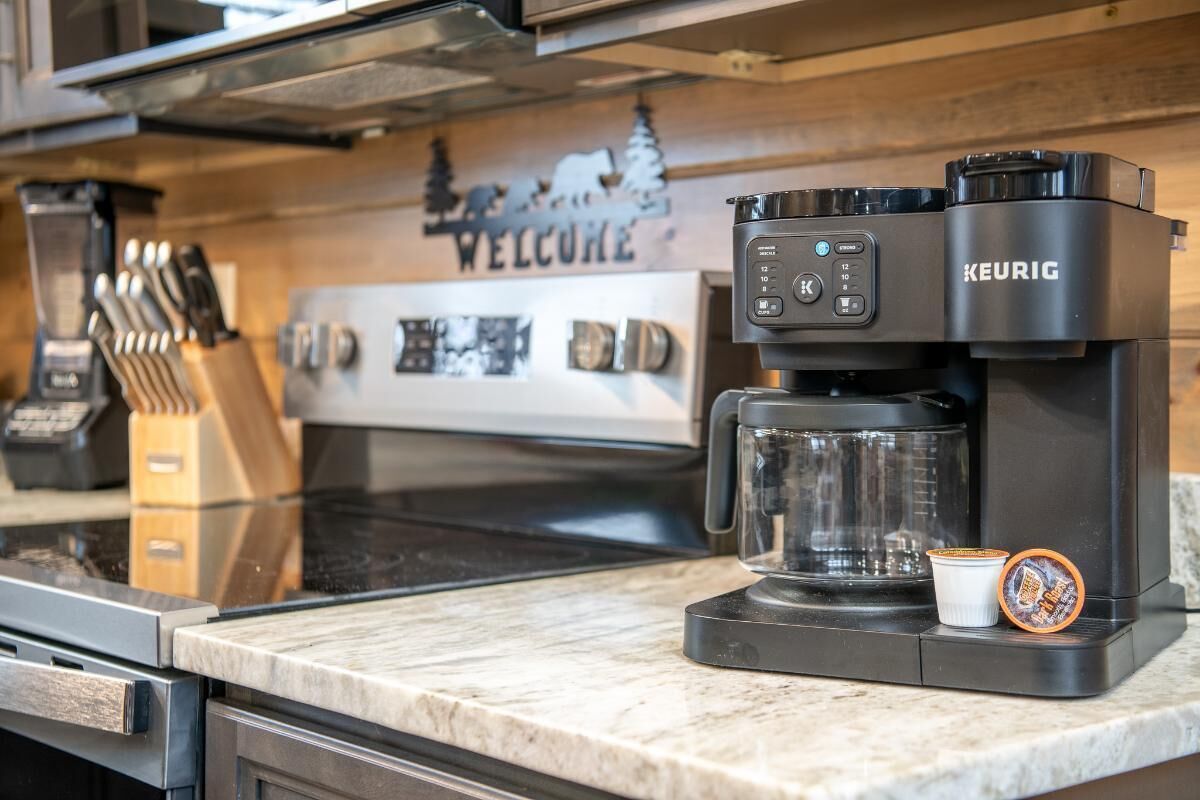 Een Keurig koffiezetapparaat op een aanrecht, met een 'WELCOME' bord erboven.