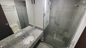 A bathroom with a granite countertop sink, a glass shower enclosure, and a toilet. - Suite with garage - Camorim (Rio de Janeiro)