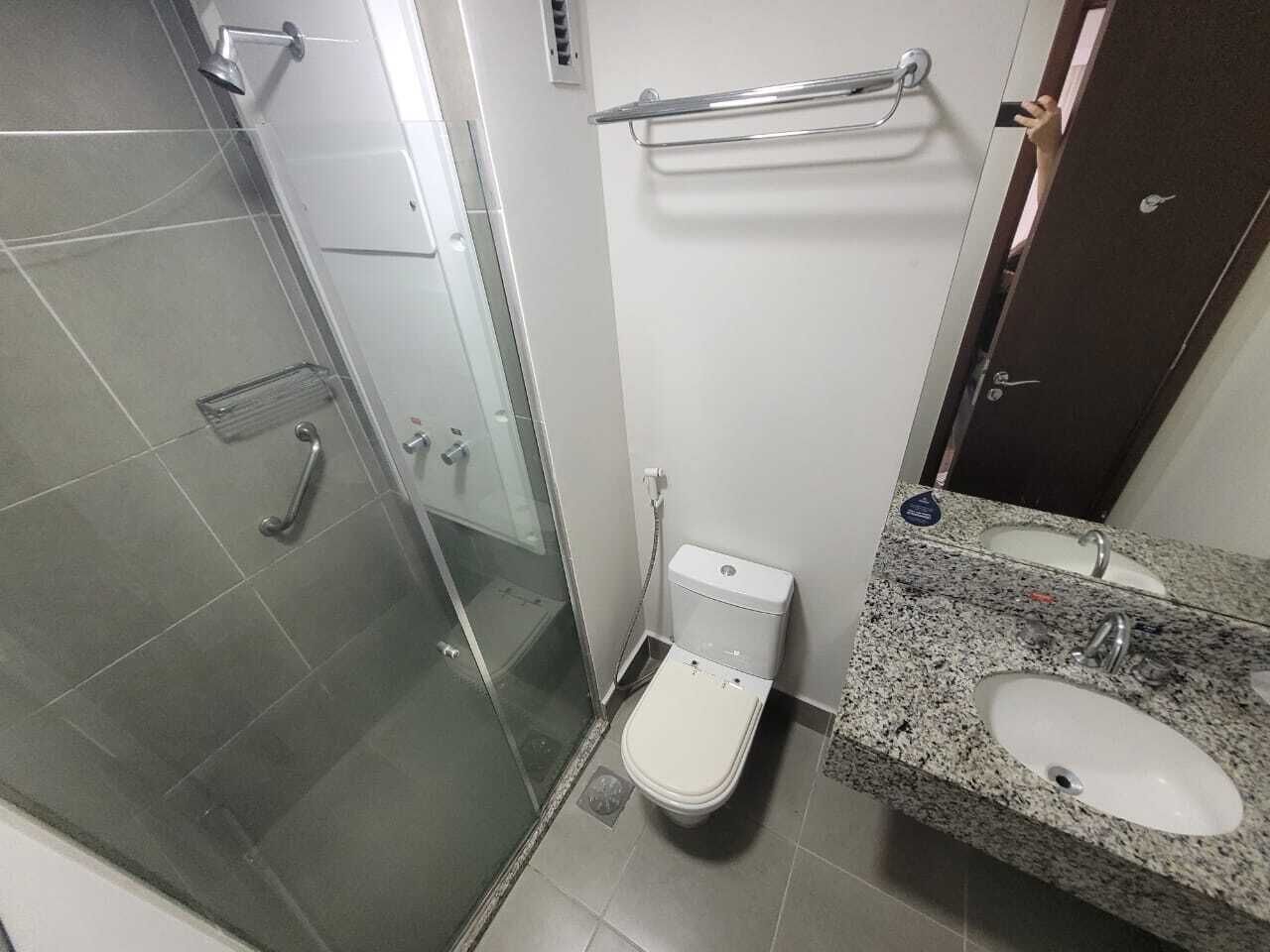 Een badkamer met een douchecabine van glas, toilet, wastafel met een granieten aanrechtblad en een handdoekrek.