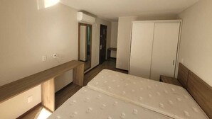 A bedroom with a bed, a desk, a wardrobe, and an air conditioning unit. - Suite with garage - Camorim (Rio de Janeiro)