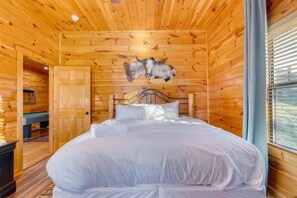 Quarto de cabana de madeira com uma cama, porta de madeira e uma janela.
