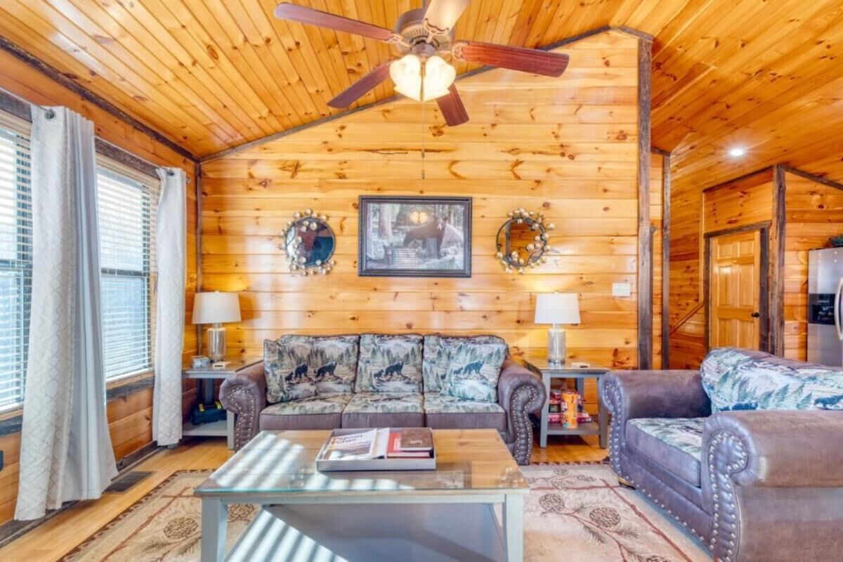Ein Blockhaus-Interieur mit Holzbalkendecke, einer Couch, einem Couchtisch und einem Kamin.