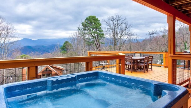 A hot tub on a wooden deck with a view of mountains. - Honey Bear Lodge (Gatlinburg)