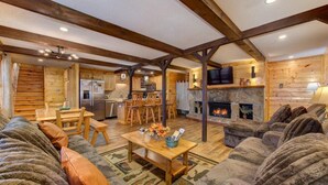 A log cabin interior with a dining area, kitchen, fireplace, and seating area. - Honey Bear Lodge (Gatlinburg)