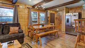 A log cabin interior with a dining area, kitchen, and a sofa. - Honey Bear Lodge (Gatlinburg)