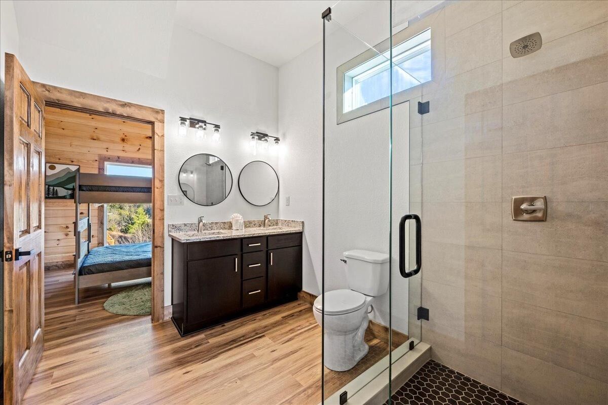 Ein modernes Badezimmer mit Duschkabine aus Glas, Holzboden, integriertem Waschbecken und Toilette.