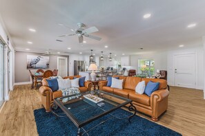 A spacious living room with a leather sofa, a glass coffee table, and a dining area in the background. - Capecation! A Boater's Paradise, easy & quick out. (Cape Coral)