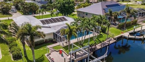 Zona residencial con piscina, paneles solares y un muelle que se adentra en el agua.