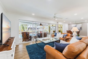 A spacious living room with a glass coffee table, leather sofas, and a large flat-screen TV. - Capecation! A Boater's Paradise, easy & quick out. (Cape Coral)