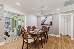 A dining area with a glass-top table, wooden chairs, and a ceiling fan. - Capecation! A Boater's Paradise, easy & quick out. (Cape Coral)