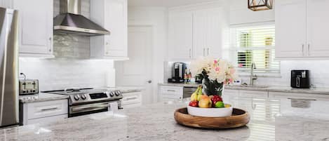 Una cocina moderna con armarios blancos, electrodomésticos de acero inoxidable y una encimera de mármol.