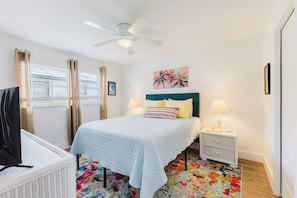 A bedroom with a bed, a ceiling fan, a nightstand, a TV, and a window with curtains. - Capecation! A Boater's Paradise, easy & quick out. (Cape Coral)