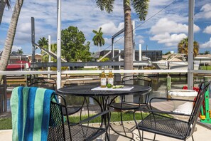 Un patio con mesas al aire libre, una mesa con bebidas y vistas a un canal con barcos.