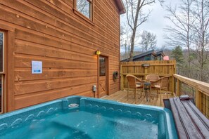 A wooden cabin with a hot tub and outdoor seating. - Sleeping Bear Hideaway (Sevierville)