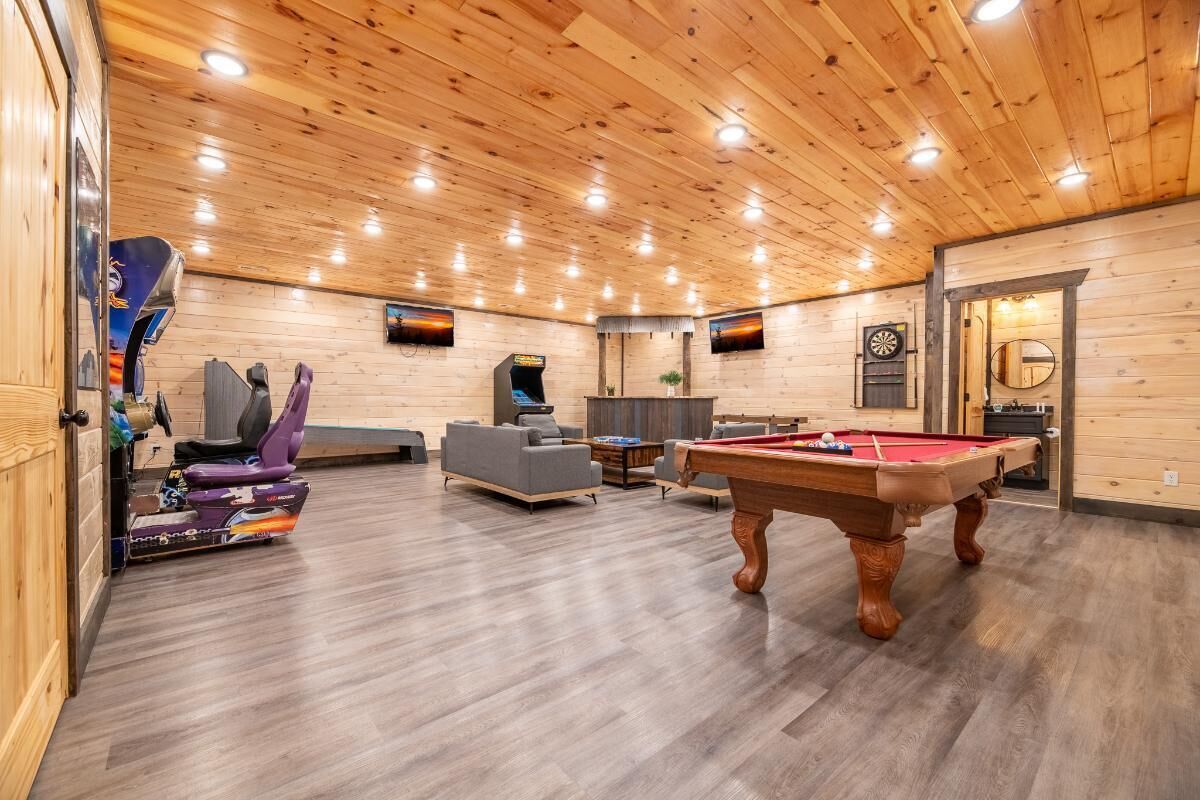 A spacious indoor area with a pool table, sofas, and arcade machines.