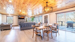 Un vaste espace de vie doté d’une cheminée, d’une table à manger avec des chaises et d’une grande fenêtre donnant sur une terrasse.