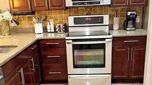 Una cocina con armarios de madera, un microondas, un horno y una cafetera.