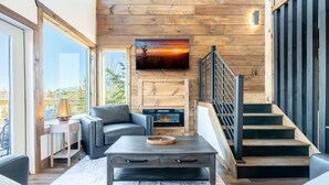 Una sala de estar moderna con chimenea, una escalera y un ventanal grande.