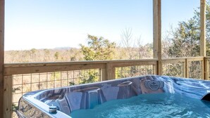 Un jacuzzi con plataforma de madera y vista a un paisaje boscoso.