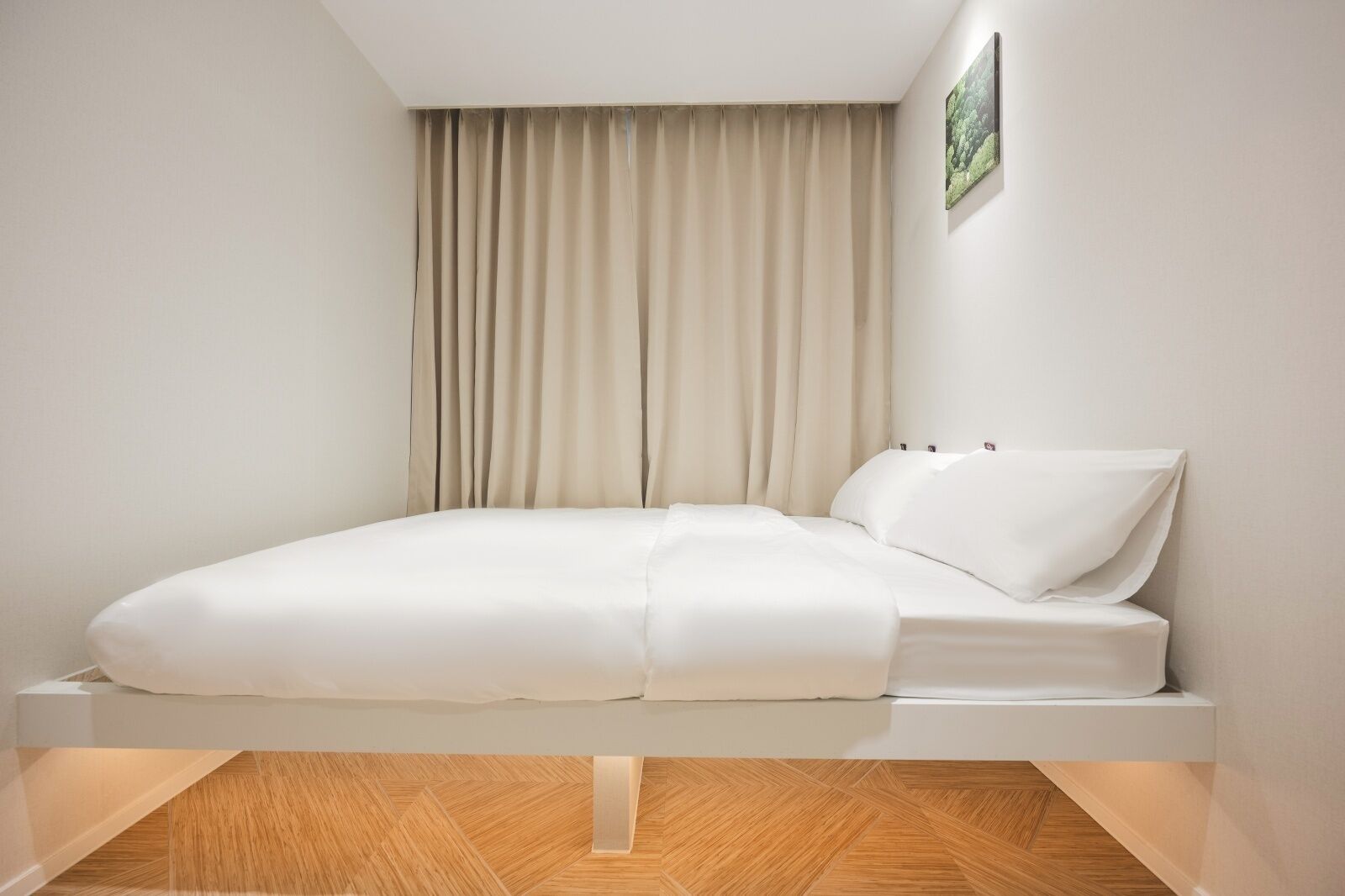 A modern bedroom with a bed, curtains, and a wooden floor.