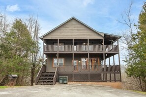 Eine zweistöckige Lodge mit Balkon, Treppe und überdachter Veranda.