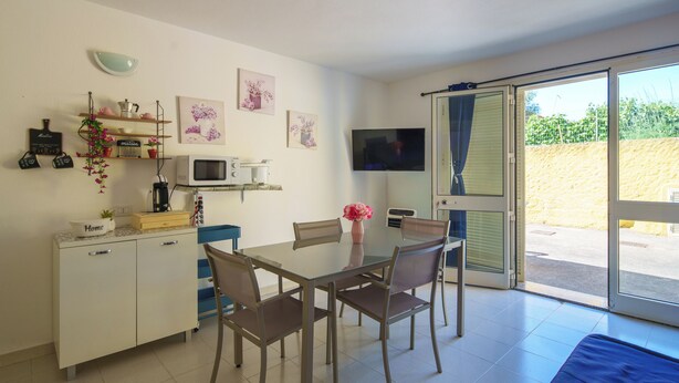 A compact kitchen with a microwave, coffee maker, and a dining table with chairs. - SpiaggiaSogno da Giò (San Teodoro)