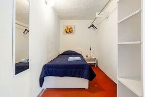 A narrow room with a bed, a bedside table, a mirror, and a wall-mounted painting. - Cozy Apartment in Trendy Condesa (Ciudad de México)