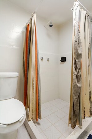 A bathroom with a toilet, shower, and a towel rack with multiple towels. - Cozy Apartment in Trendy Condesa (Ciudad de México)