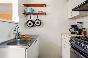 A compact kitchen with a sink, stove, and hanging pots. - Cozy Apartment in Trendy Condesa (Ciudad de México)