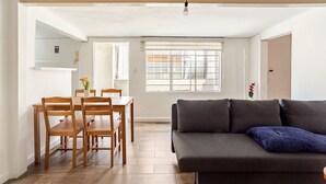 Ein Wohnzimmer mit einem dunklen Sofa, einem Holzesstisch und Stühlen.