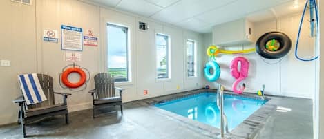 An indoor swimming pool with clear pool rules, no diving signs, and colorful inflatable toys.